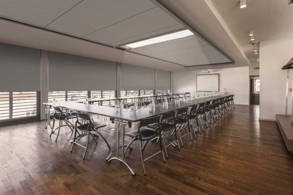 Großer Konferenzraum mit grauen Innenjalousien und Rollläden