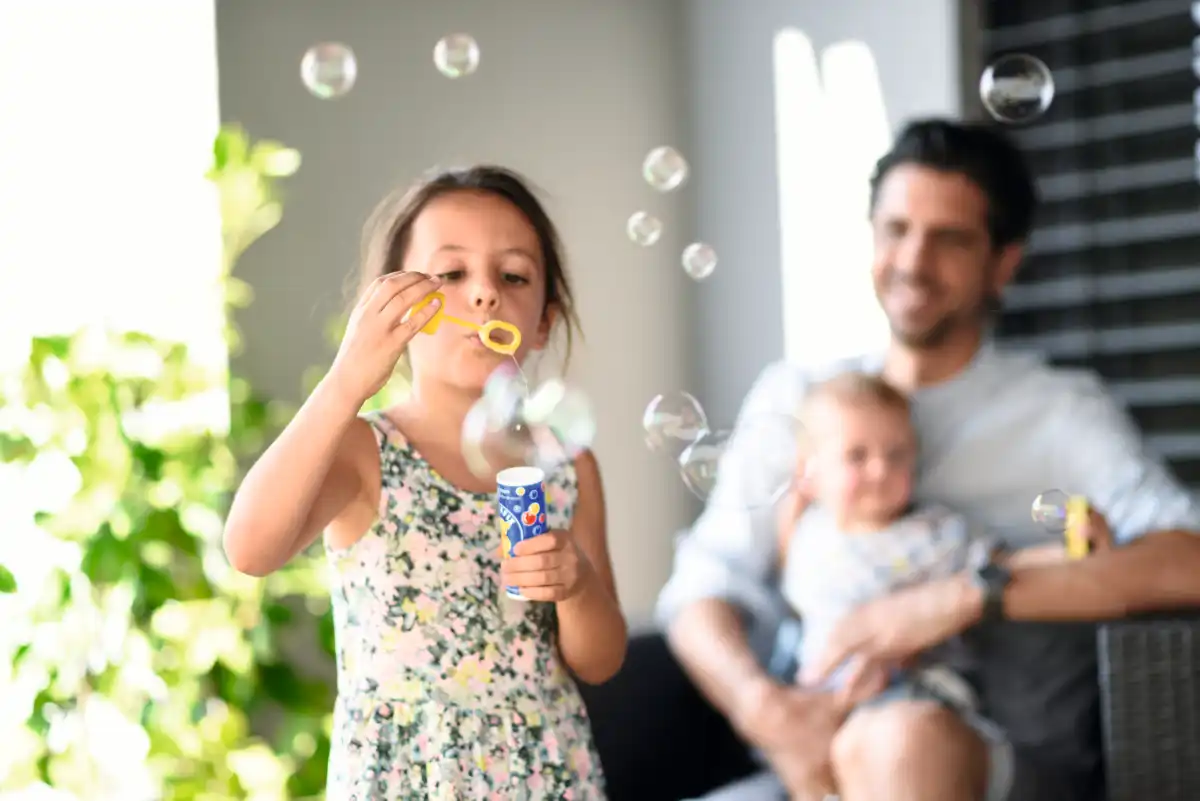 Kind spielt mit Seifenblasen im Garten