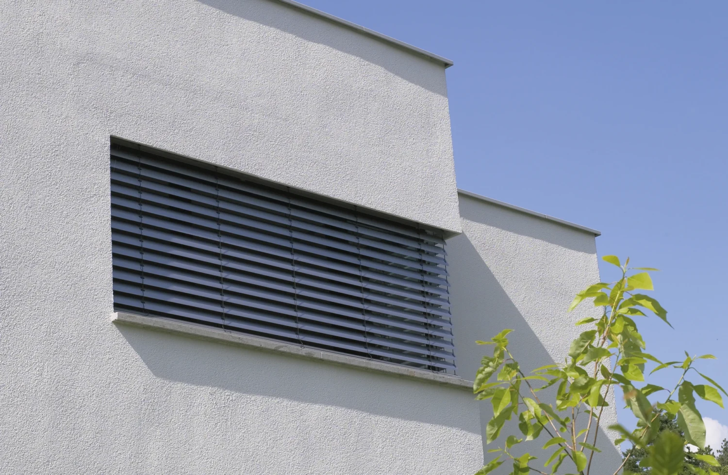 Moderne Jalousie an einem weißen Gebäude bei sonnigem Wetter